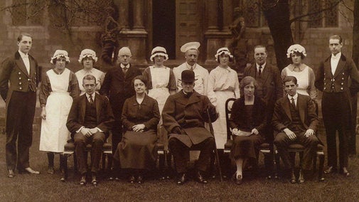 Smart man seated with two rows of staff in formal uniform